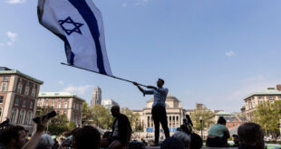 Columbia University students wave a large Israeli flag over pro-Palestinian protesters on campus