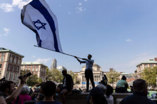 Columbia University students wave a large Israeli flag over pro-Palestinian protesters on campus